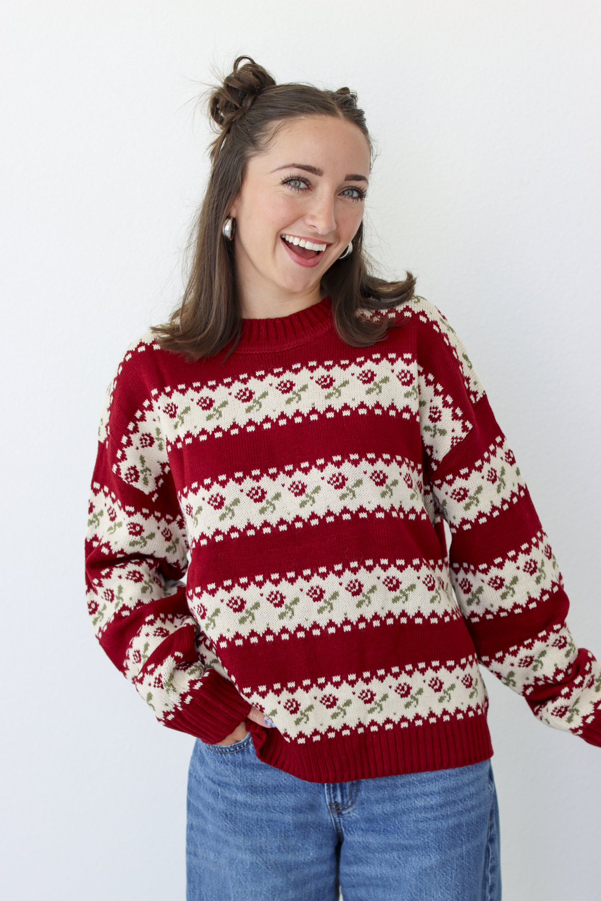 Woman wearing a red sweater with roses and blue denim jeans 