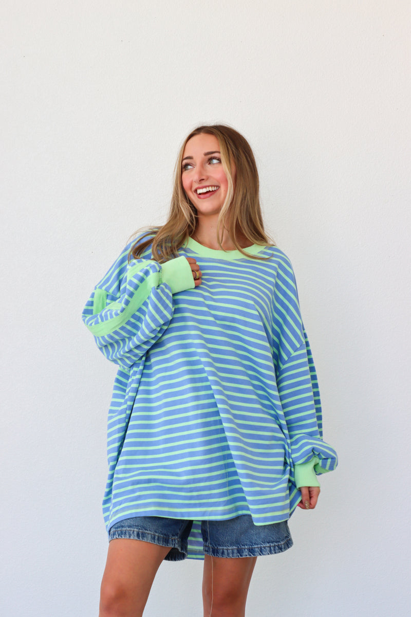 Woman wearing a blue and green striped sweater against a white background