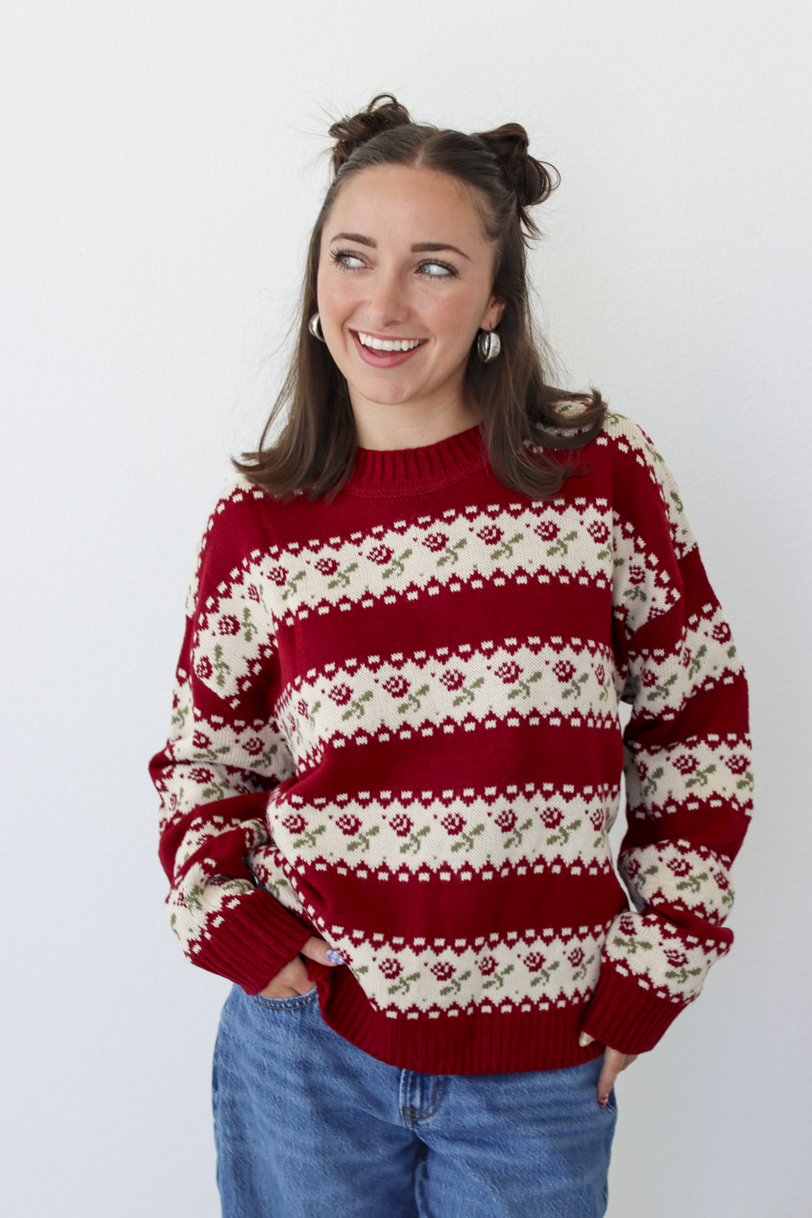 Woman wearing a red sweater with roses and blue denim jeans 