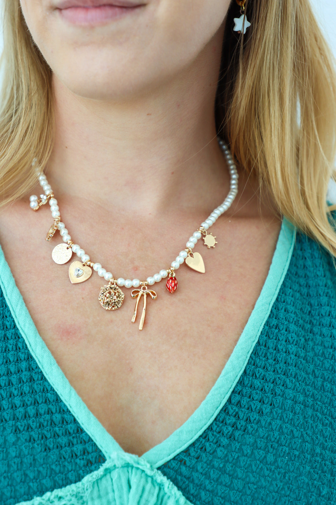 Necklace with various charms worn by a person against a white background