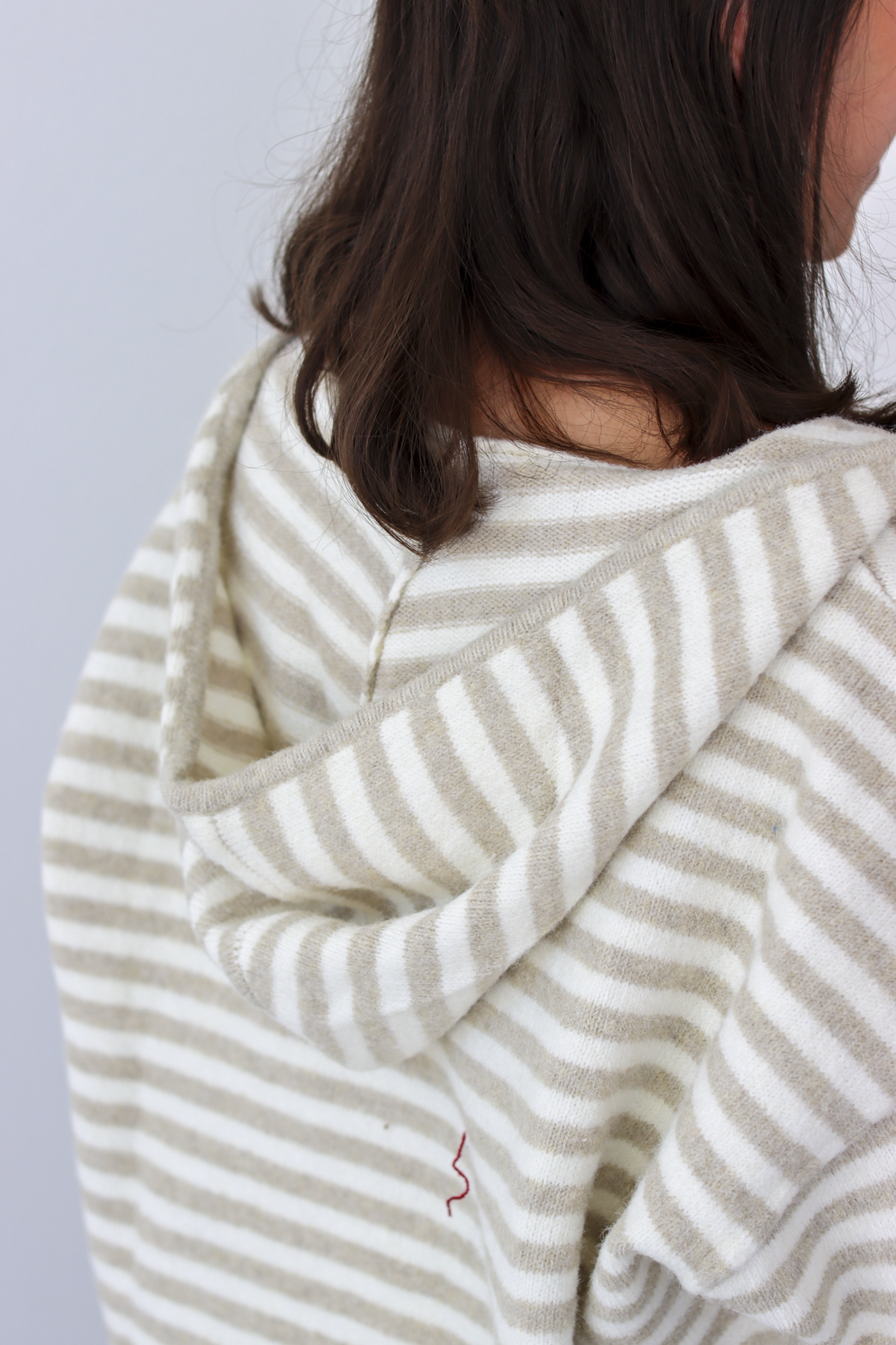 Close up of hood on tan and white stripe zip-up sweater