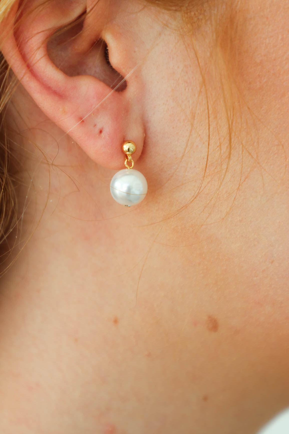 girl wearing gold pearl earrings
