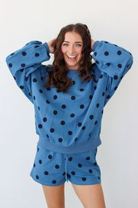 Woman wearing a blue sweater and shorts outfit set with black polka dots