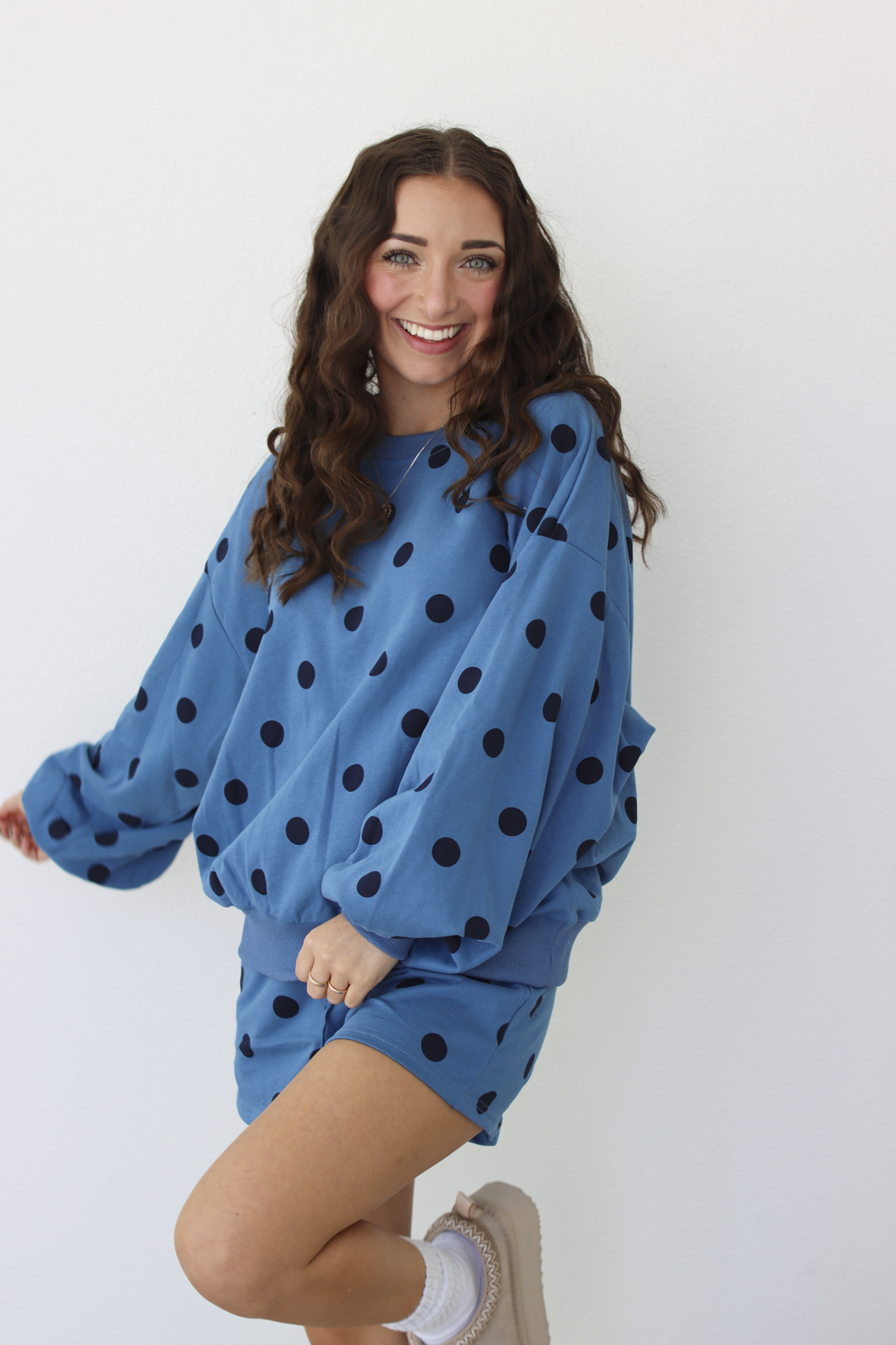 Woman wearing a blue sweater and shorts outfit set with black polka dots