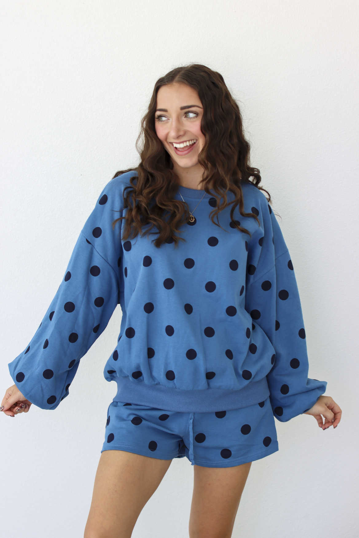 Woman wearing a blue sweater and shorts outfit set with black polka dots
