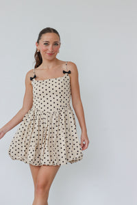 girl wearing cream dress with black polka dots and bow detailing