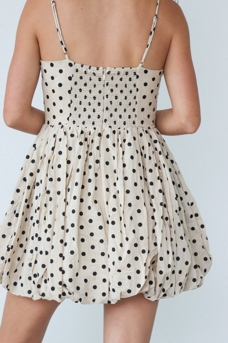 girl wearing cream dress with black polka dots and bow detailing
