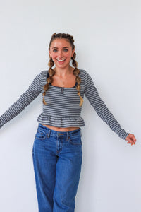 Woman wearing a striped long-sleeve top and blue jeans against a white background