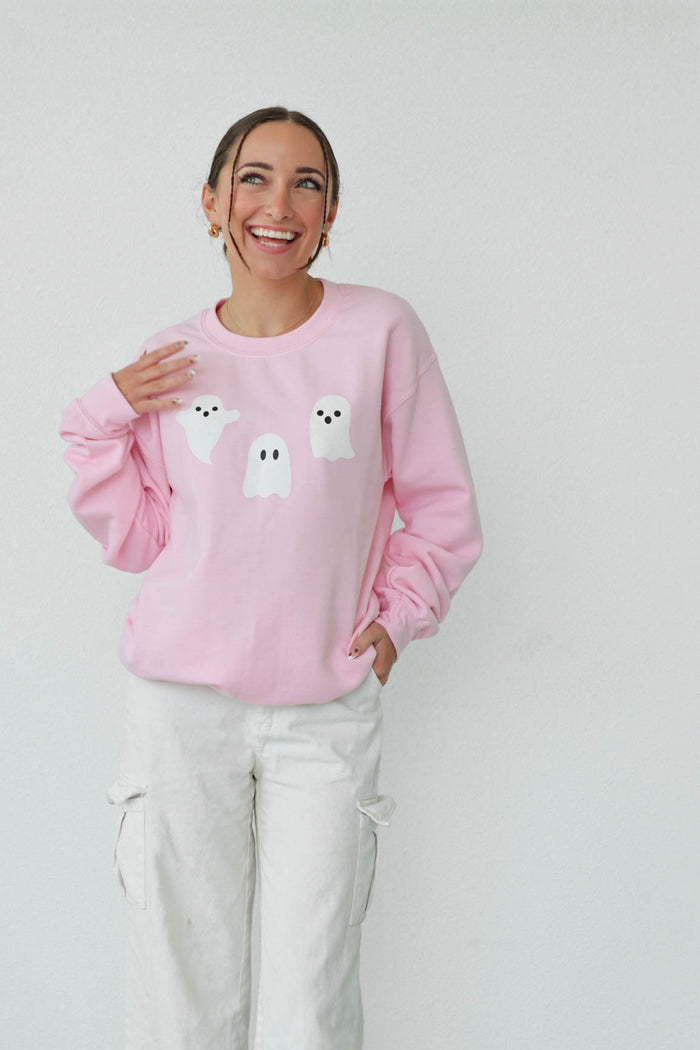 girl wearing light pink crewneck sweatshirt with halloween ghost graphics
