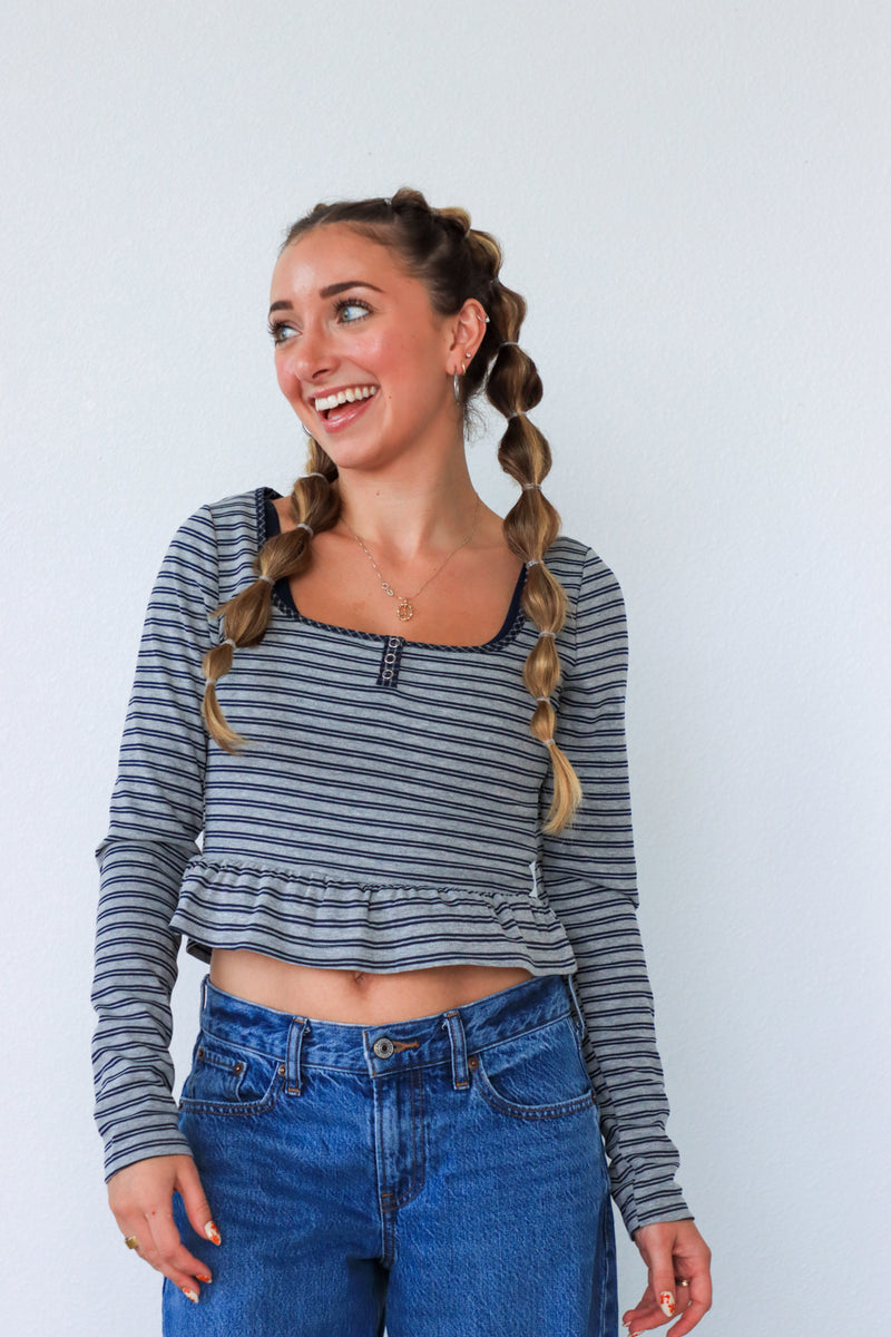 Woman with braided hair wearing a striped shirt and jeans against a white background