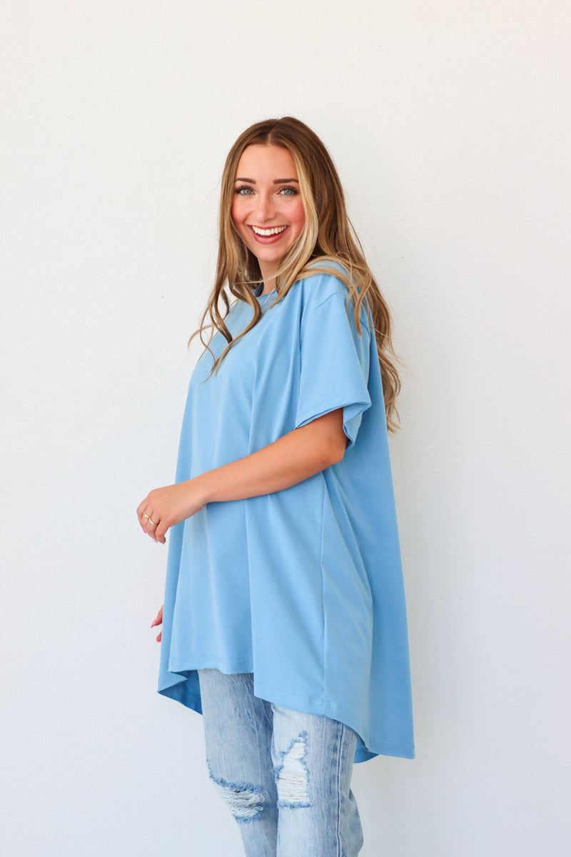Woman wearing a light blue tunic with a plain white background