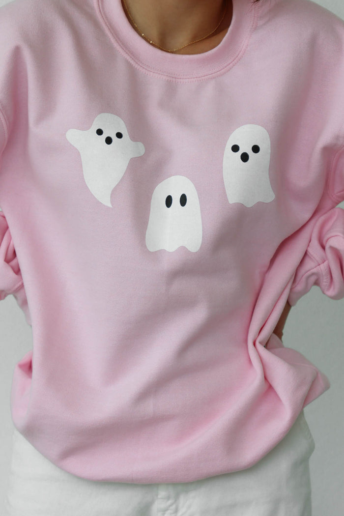 girl wearing light pink crewneck sweatshirt with halloween ghost graphics
