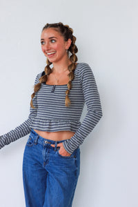 Woman wearing a striped long-sleeve top and blue jeans against a white background