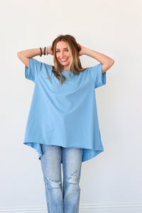 Woman wearing a light blue oversized t-shirt and jeans against a white background