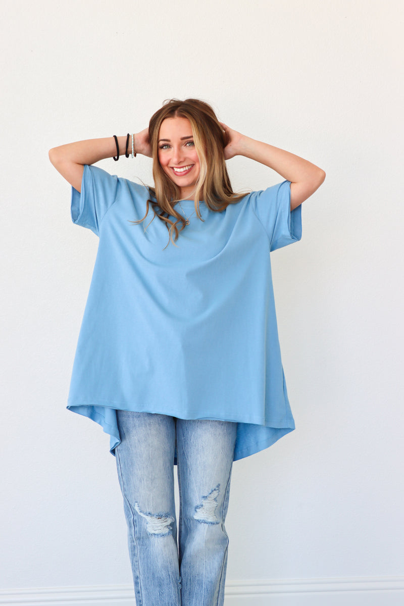 Woman wearing a light blue oversized t-shirt and jeans against a white background