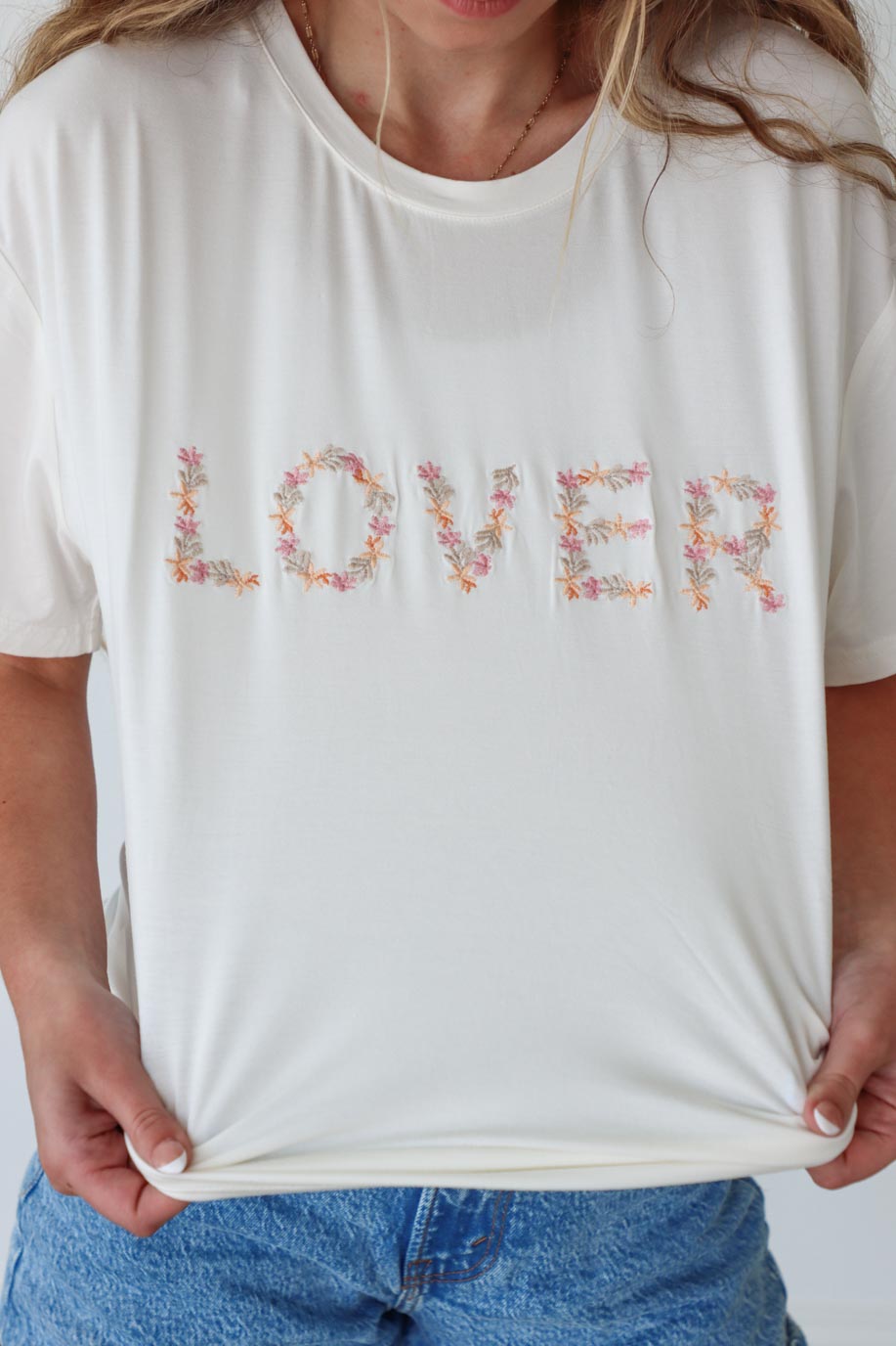 girl wearing white t-shirt with embroidered "lover" graphic