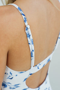 girl wearing white one piece swimsuit with blue floral pattern