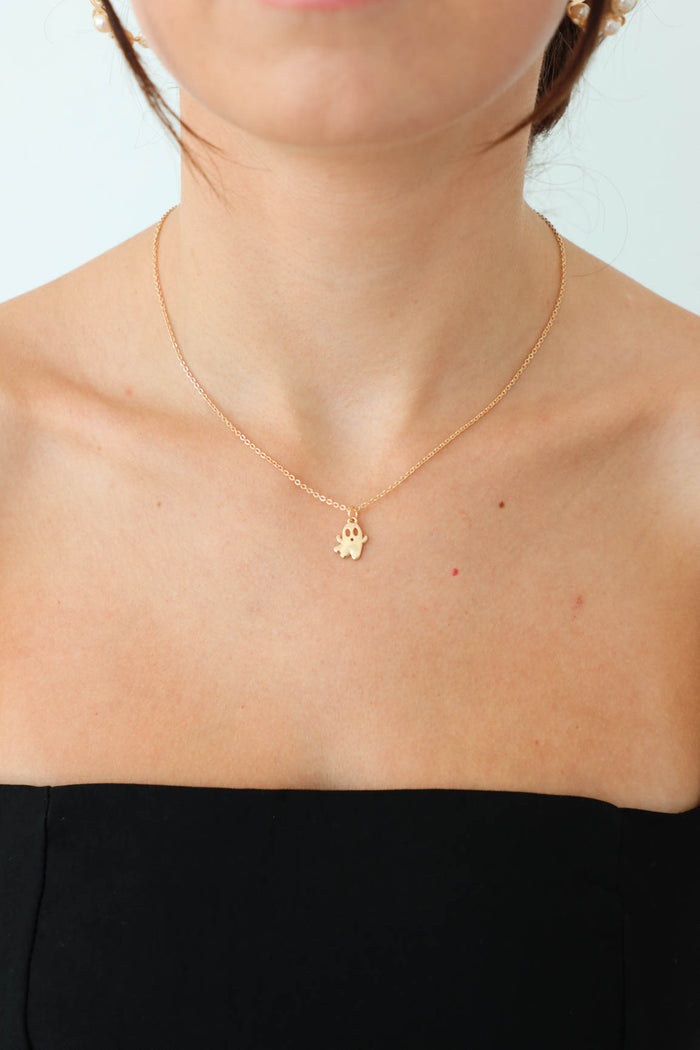 girl wearing small, gold ghost necklace