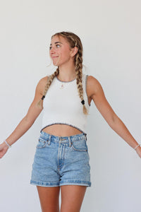girl wearing white knitted tank top with black contrast stitch detailing