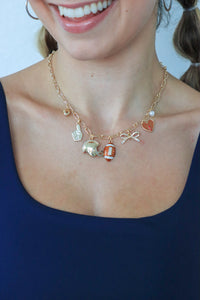 Necklace with various charms worn by a person against a white background