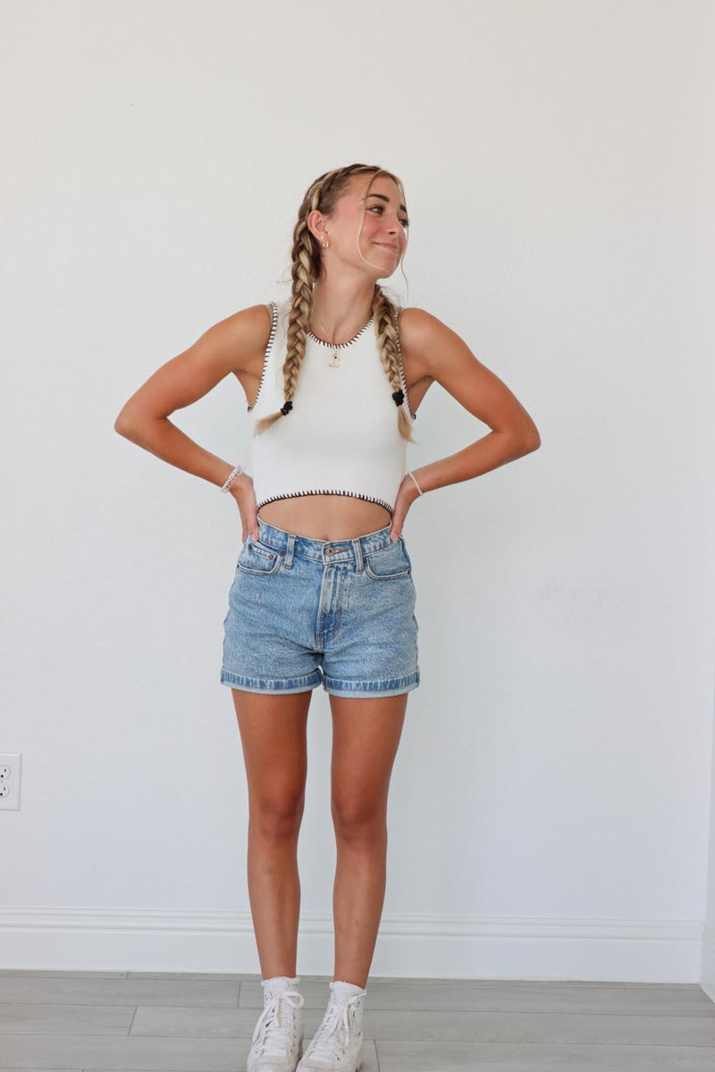 girl wearing white knitted tank top with black contrast stitch detailing