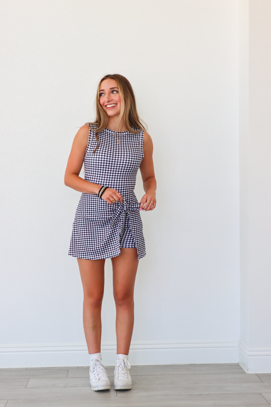Woman wearing a checkered dress standing against a white wall