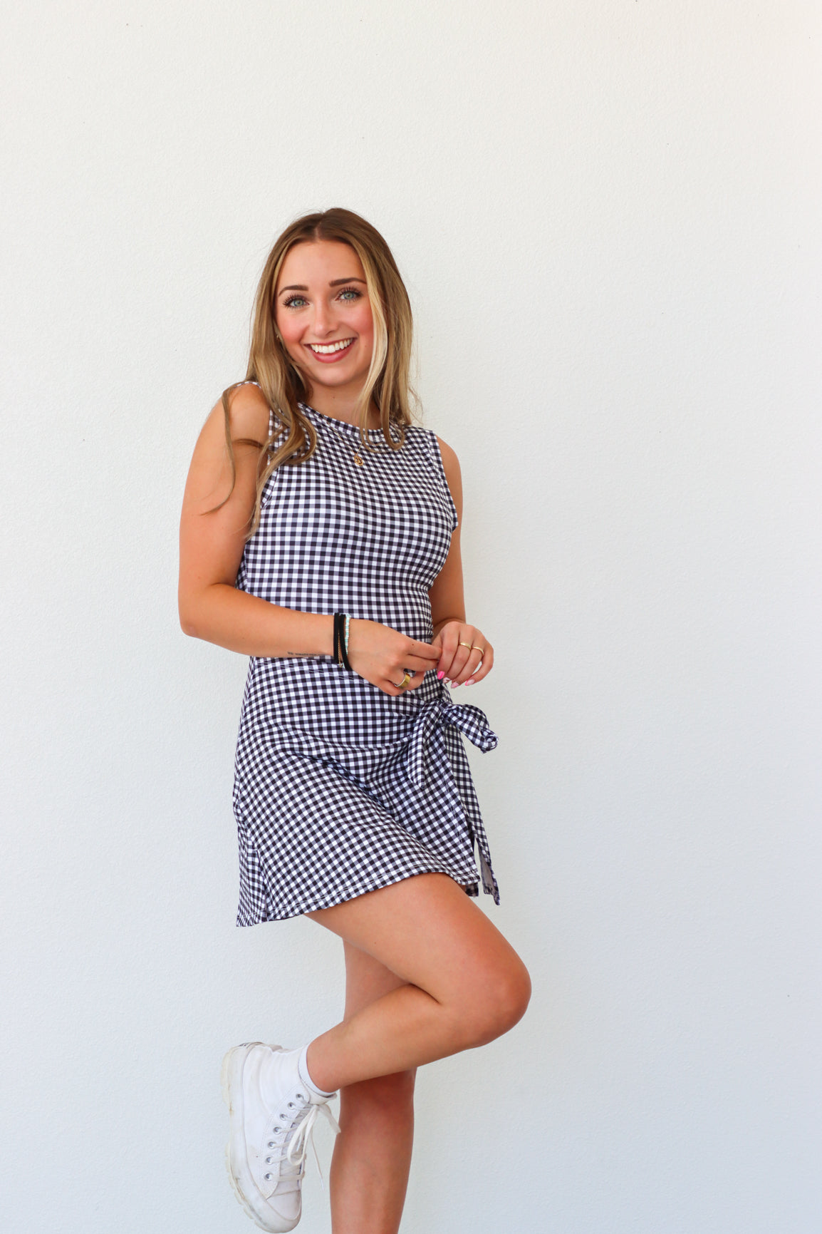 Woman wearing a blue and white checkered dress against a plain background