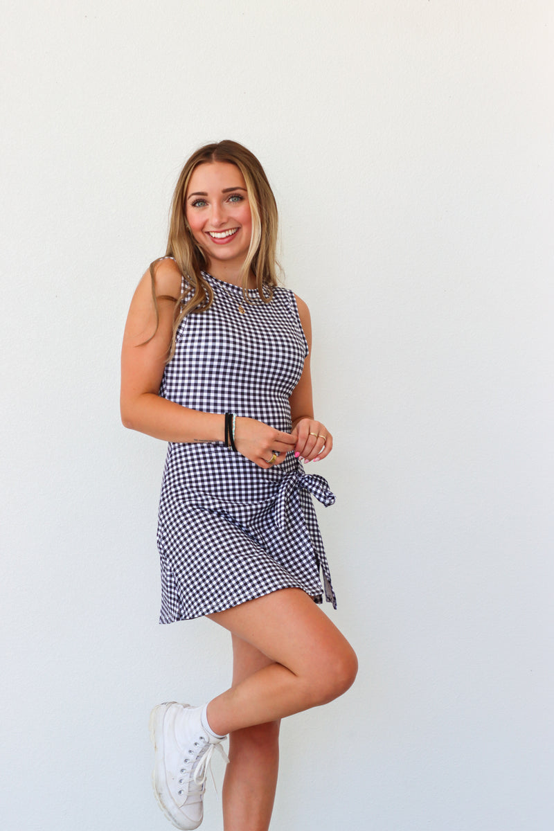 Woman wearing a blue and white checkered dress against a plain background