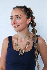 Woman wearing a large, ornate necklace against a plain background