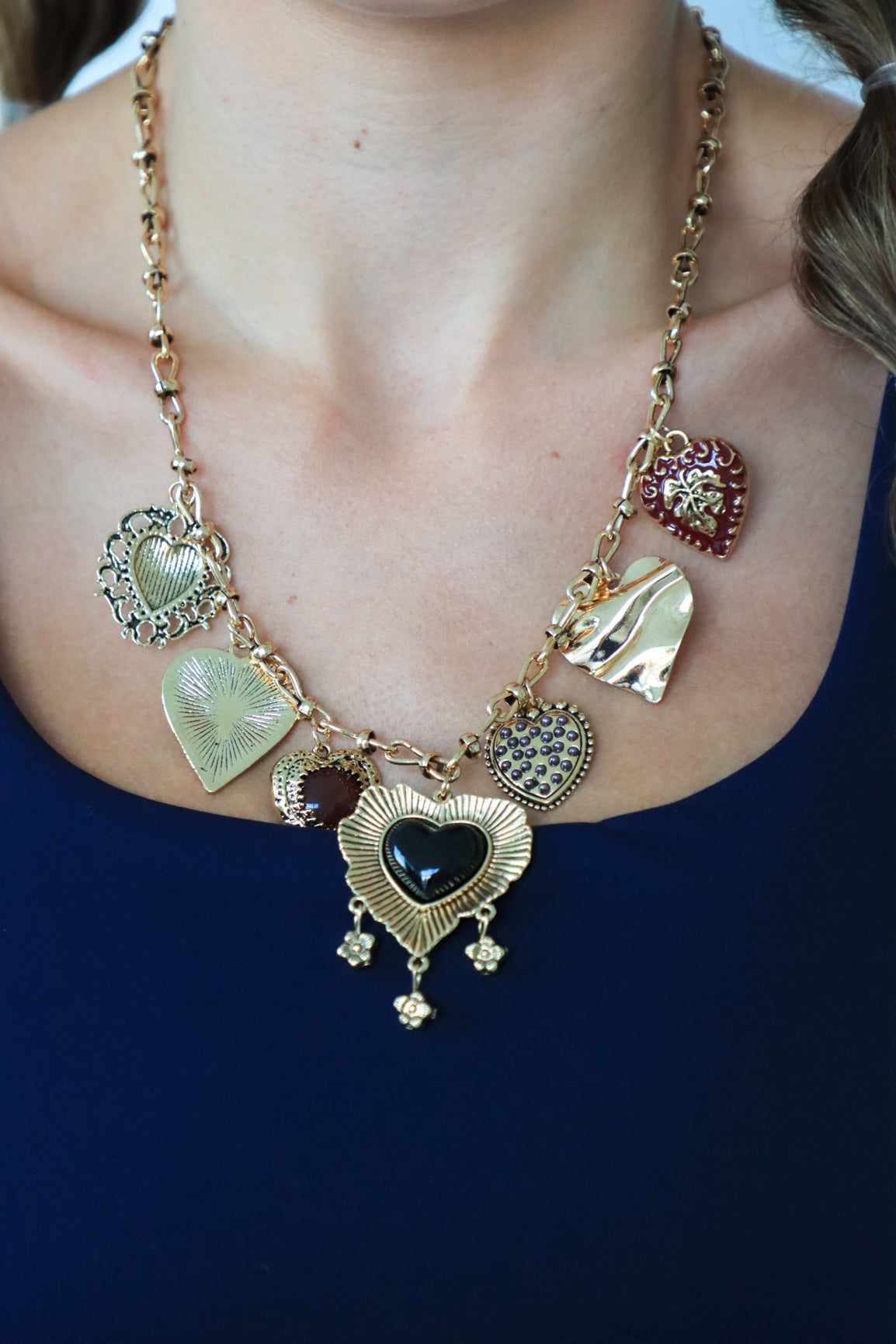 Necklace with heart-shaped charms worn by a person against a dark background