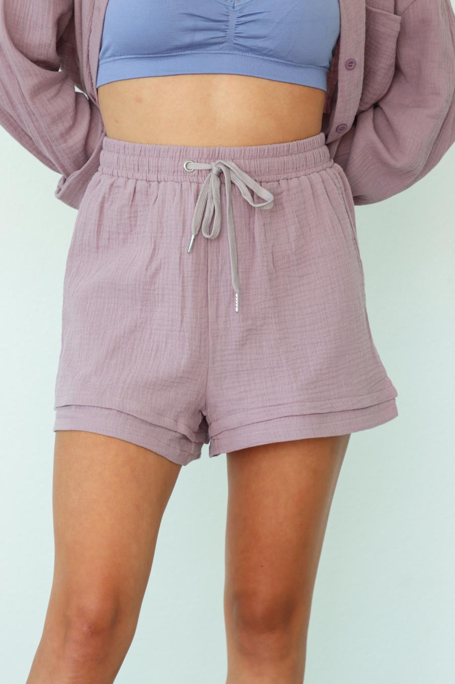 girl wearing purple matching lounge set: button up top and drawstring shorts