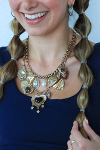 Woman wearing a gold necklace with heart-shaped pendants against a blue background