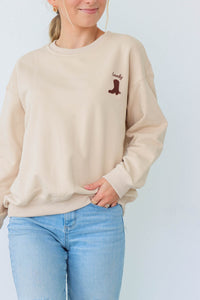 girl wearing cream crewneck with cowboy boot embroidery detailing