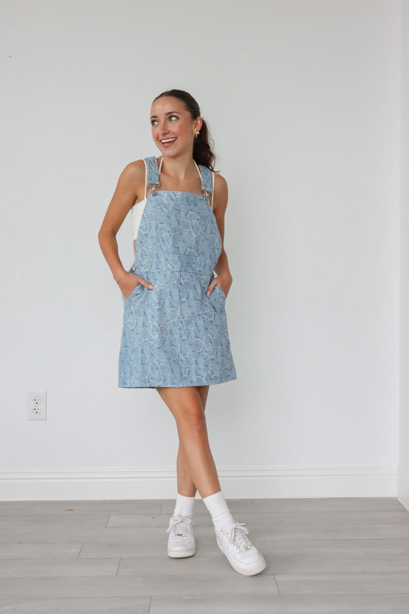 girl wearing light denim overall dress with paisley pattern