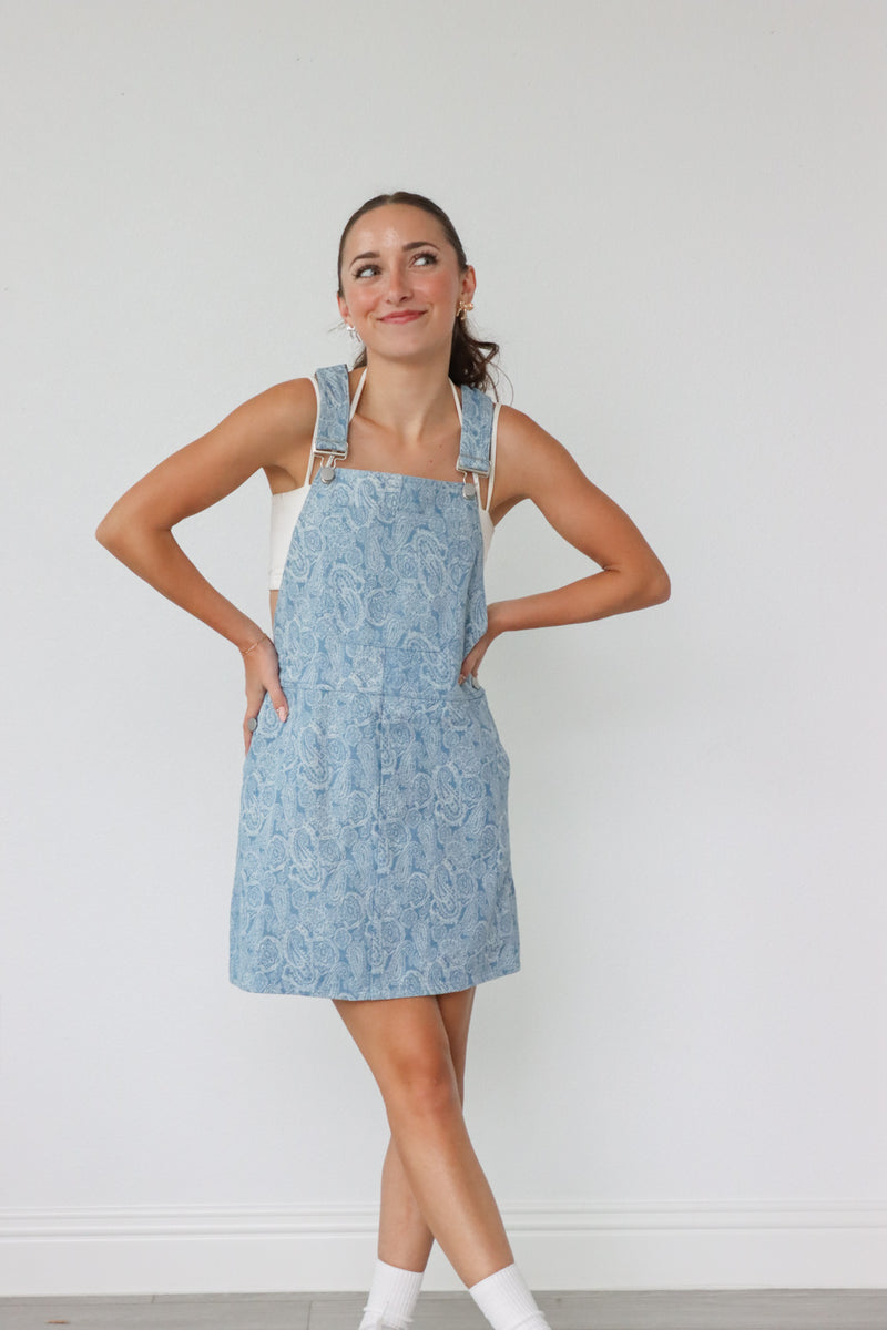 girl wearing light denim overall dress with paisley pattern