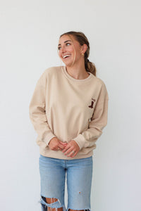 girl wearing cream crewneck with cowboy boot embroidery detailing