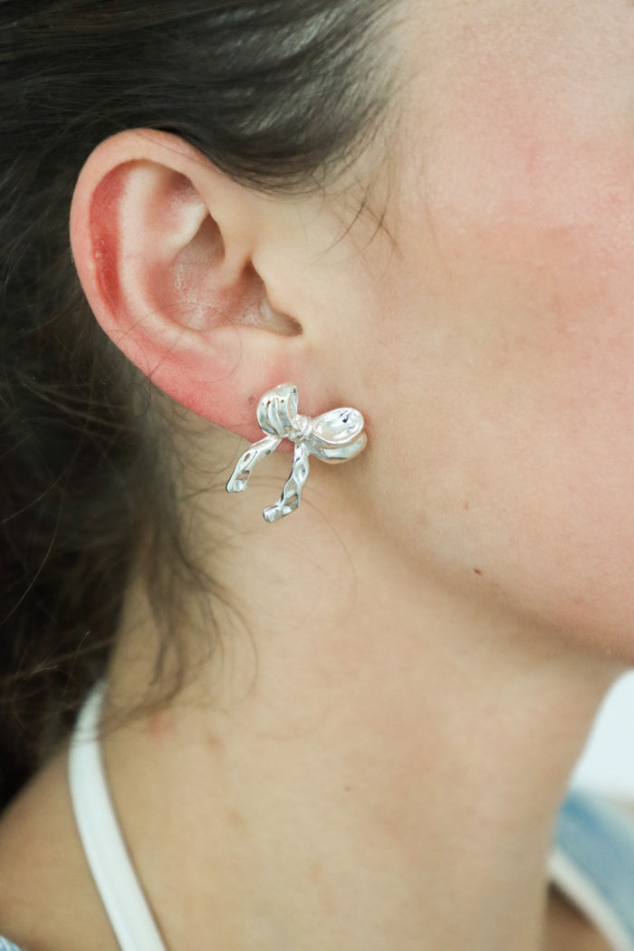 girl wearing silver bow earrings