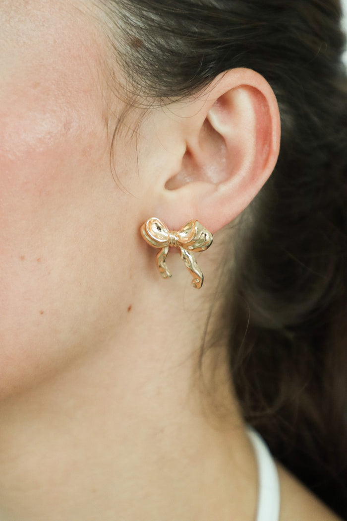 girl wearing gold bow earrings