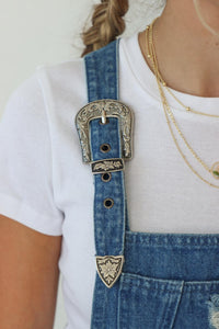 girl wearing denim overall skirt with western buckles