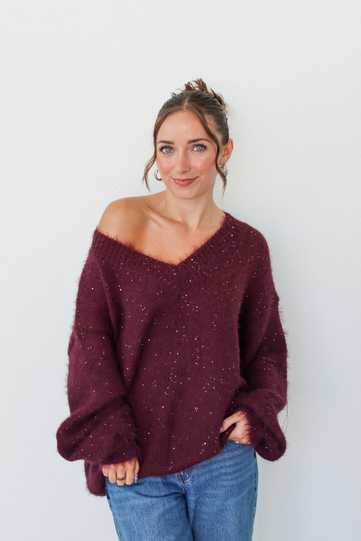 Woman wearing a dark purple sequins off the shoulder sweater