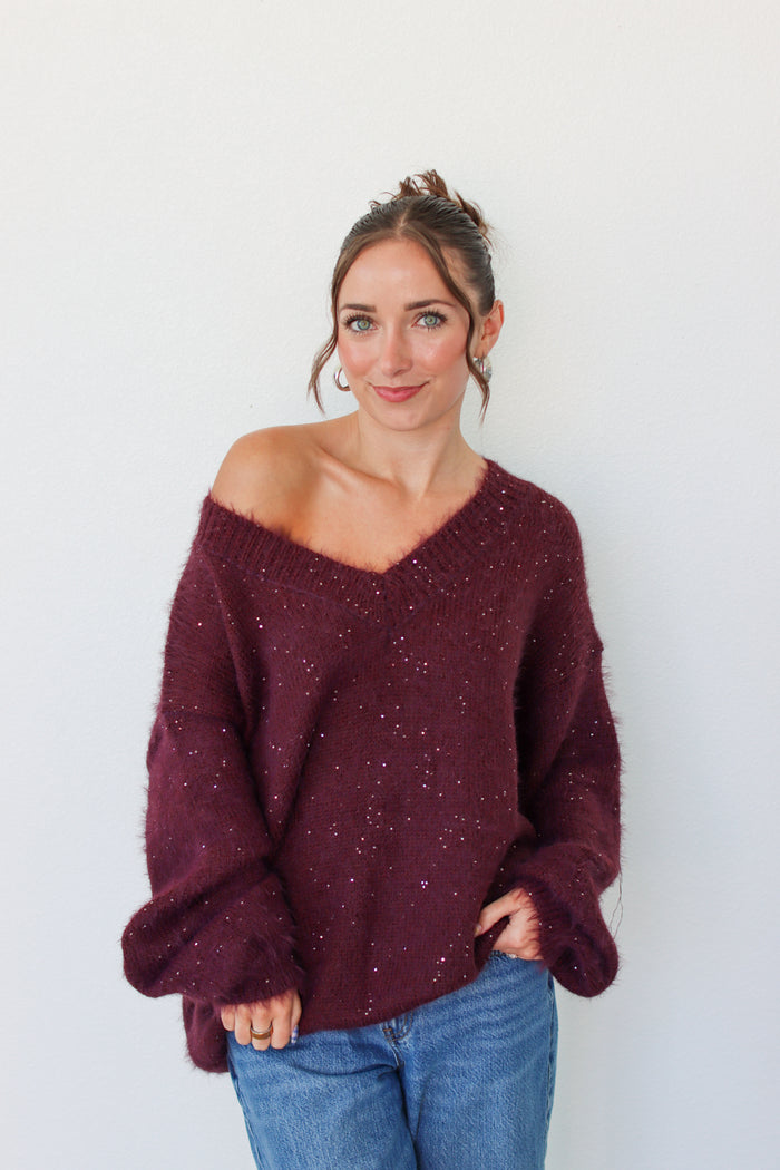 Woman wearing a dark purple sequins off the shoulder sweater