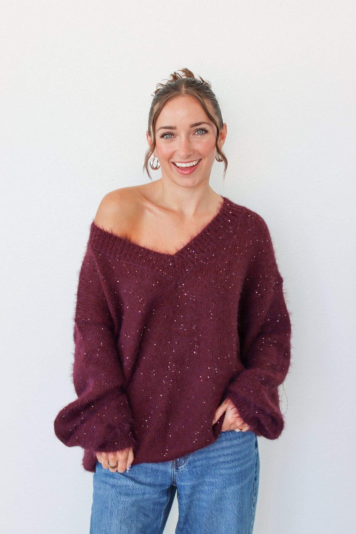 Woman wearing a dark purple sequins off the shoulder sweater