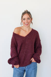 Woman wearing a dark purple sequins off the shoulder sweater