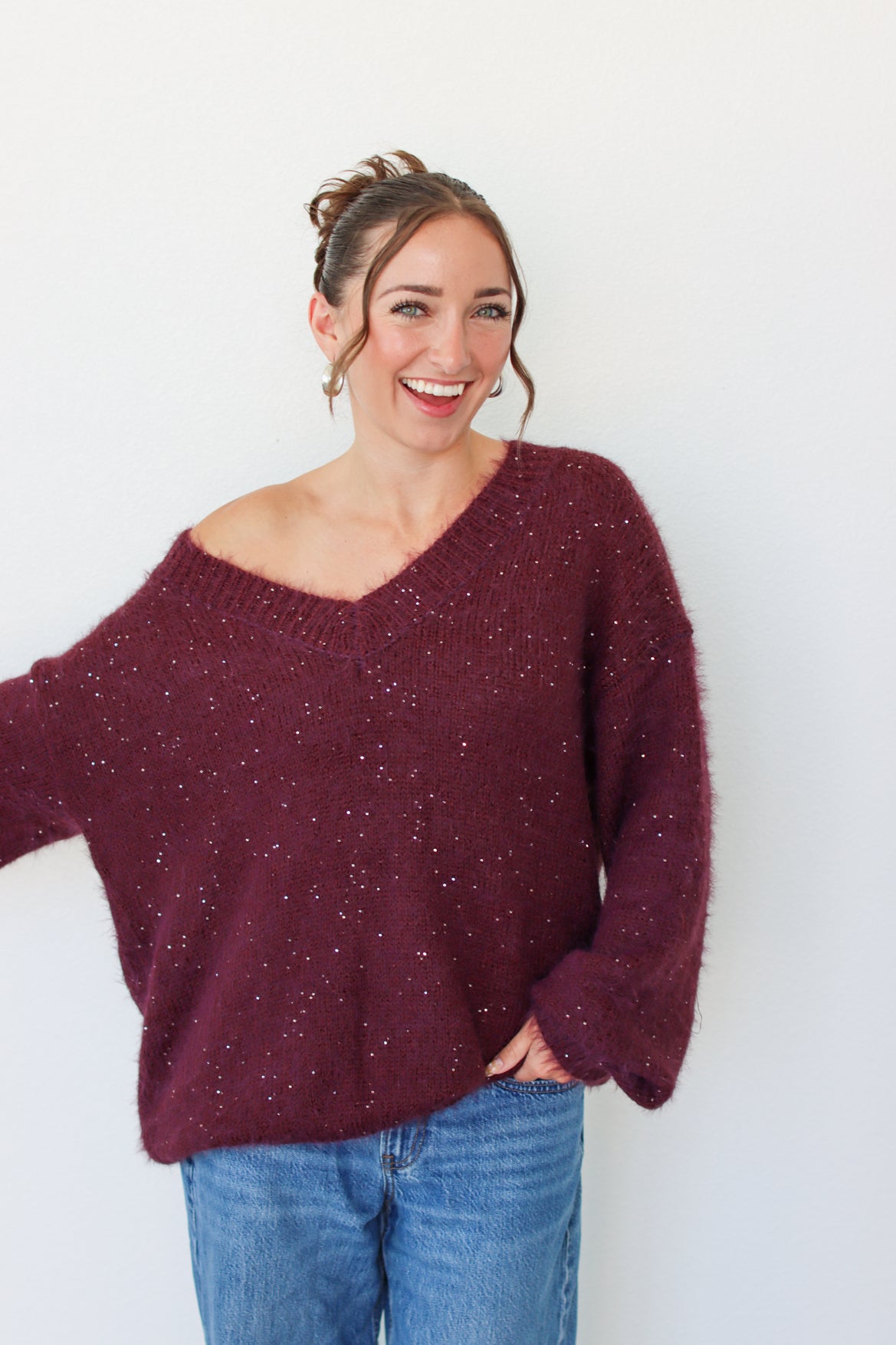 Woman wearing a dark purple sequins off the shoulder sweater