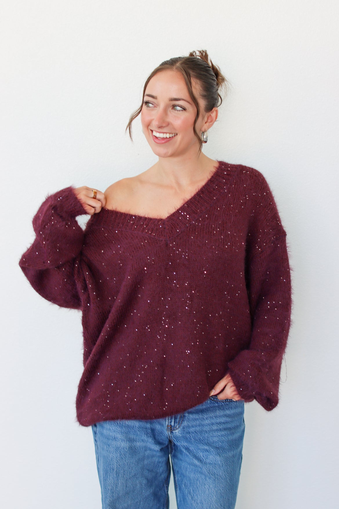 Woman wearing a dark purple sequins off the shoulder sweater