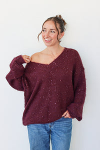 Woman wearing a dark purple sequins off the shoulder sweater