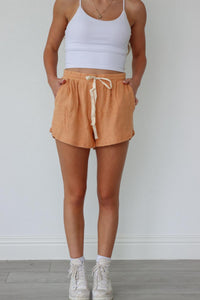 girl wearing orange comfy lounge shorts with cream drawstring