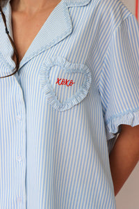 Light blue and white striped shirt with a heart-shaped pocket and 'xoxo' embroidery.