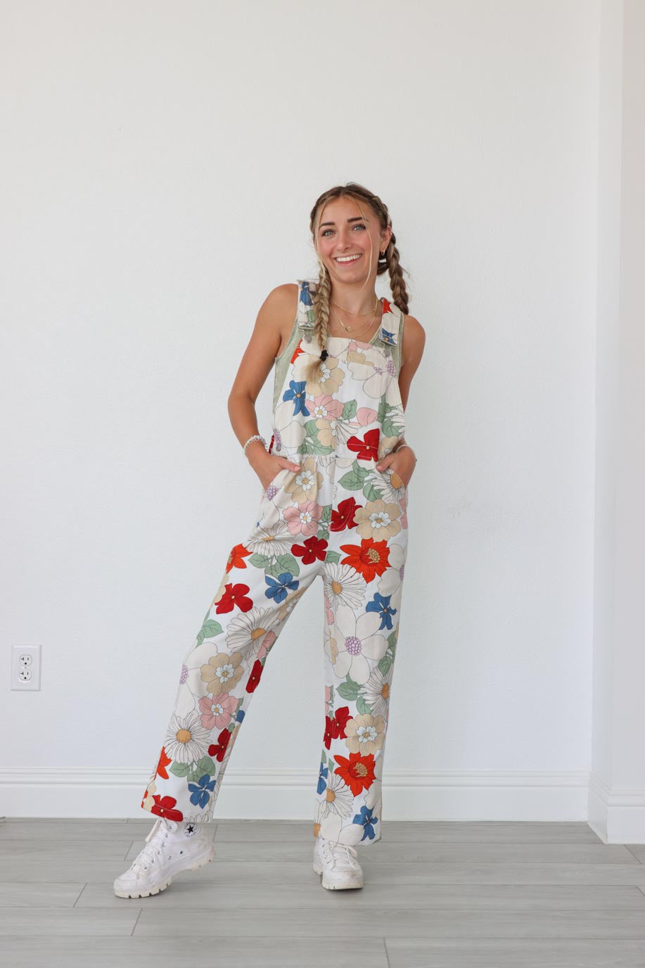 girl wearing cream long overalls with multicolored floral print