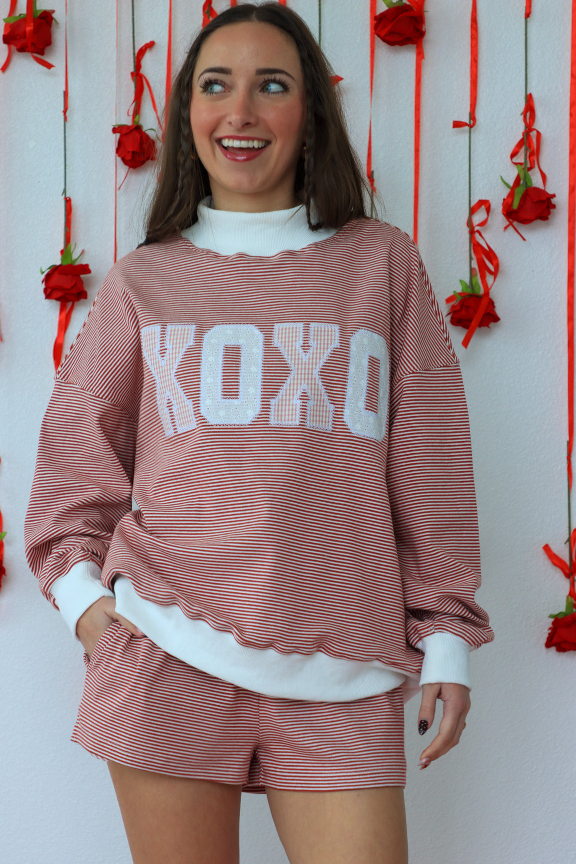 Woman wearing a pink 'XOXO' outfit with a decorative background